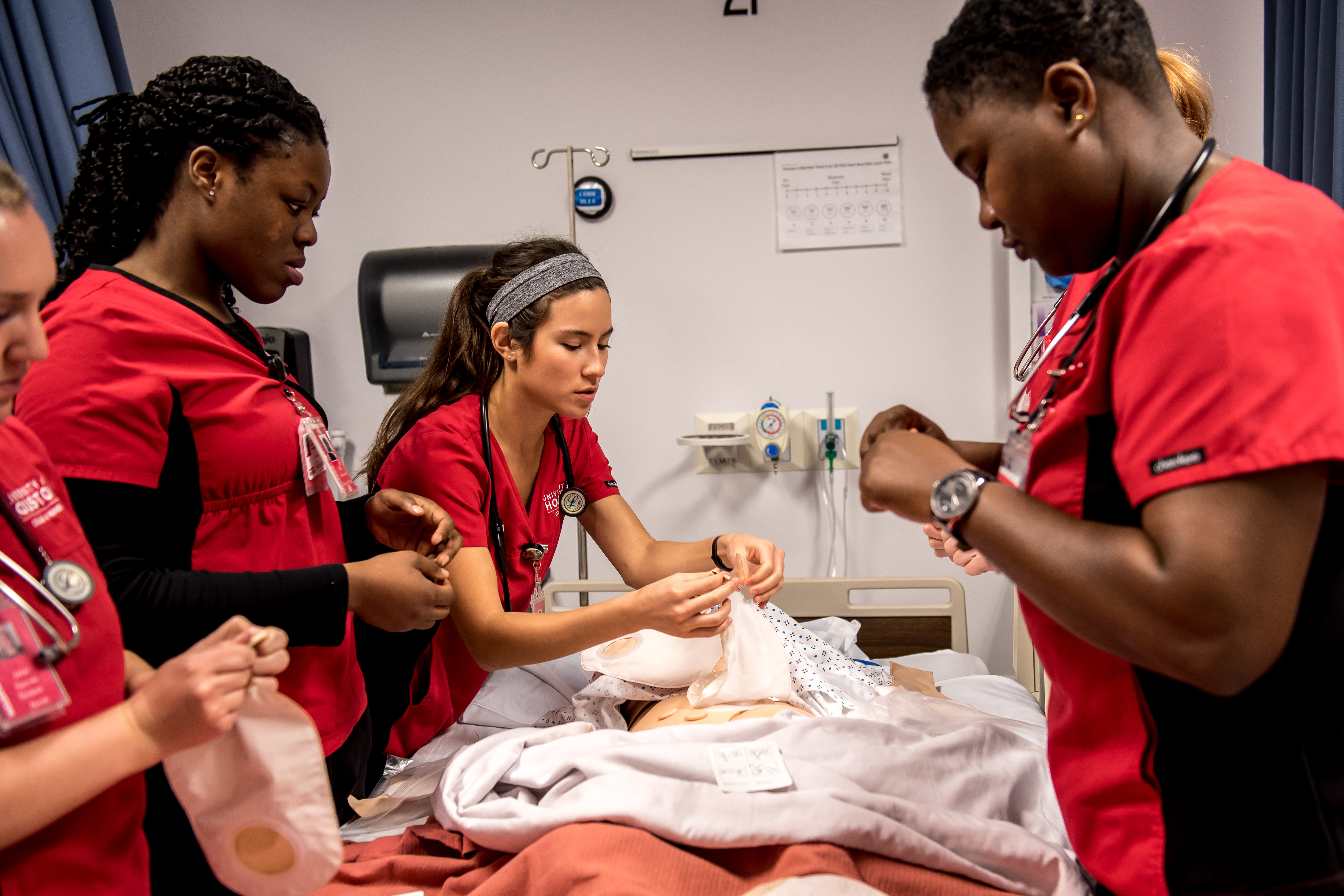 Nurse students praticing on a dummy patient laying in bed